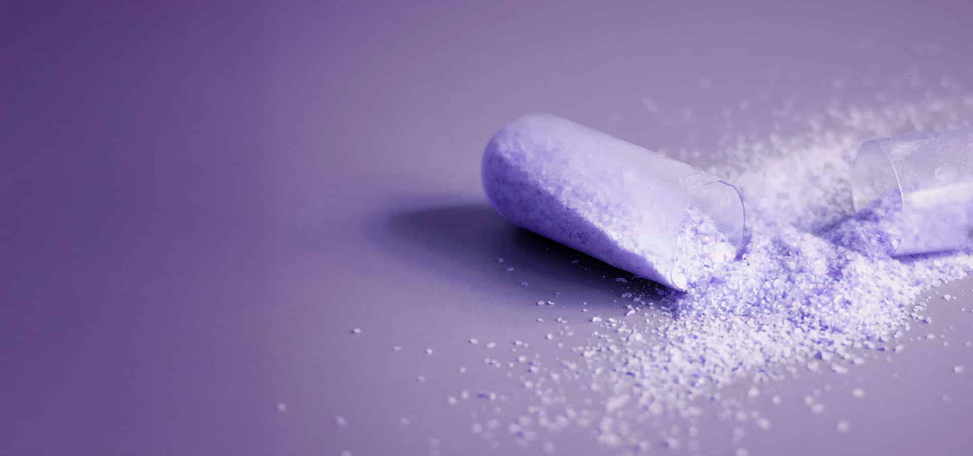 opened-medical-capsule-to-show-beige-powder-on-gre-1-1
